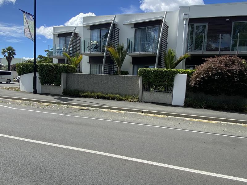 Low clipped hedges and planters along the street frontage of a row of townhouses